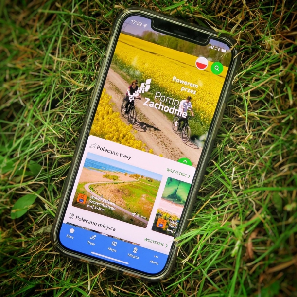 Smartfon położony na trawie. Na ekranie wyświetla się napis 