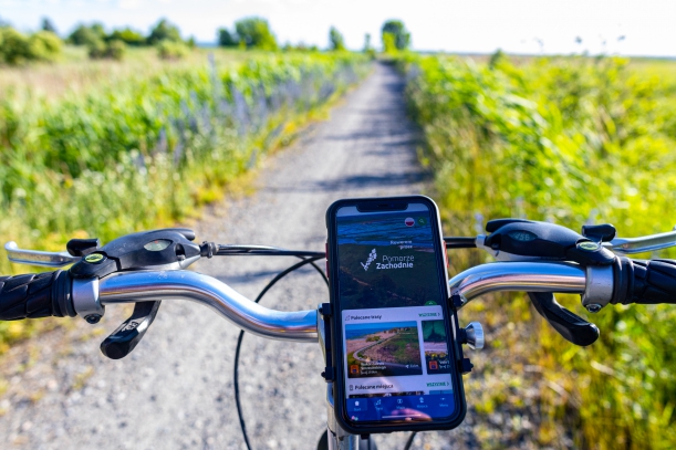 Smartfon zamocowany na kierownicy roweru. Na ekranie wyświetlony napis 