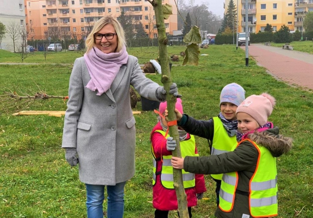 Członkini zarządu województwa Anna Bańkowska i troje przedszkolaków przy młodym drzewie, posadzonym w ramach akcji Pomorze Zachodnie - Zielony Region