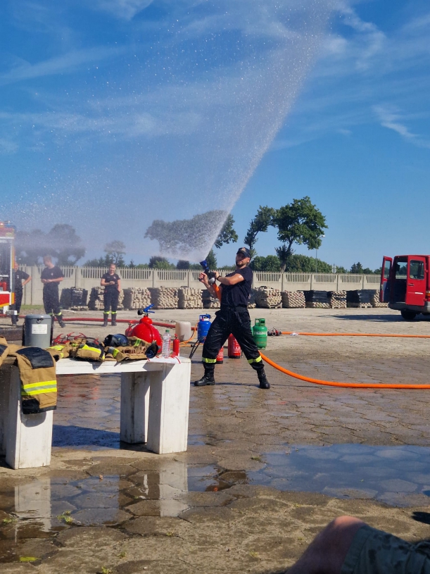strażak prezentuje sprzęt i deponstruje jak prawidłowo polewać wodą pod ciśnieniem 